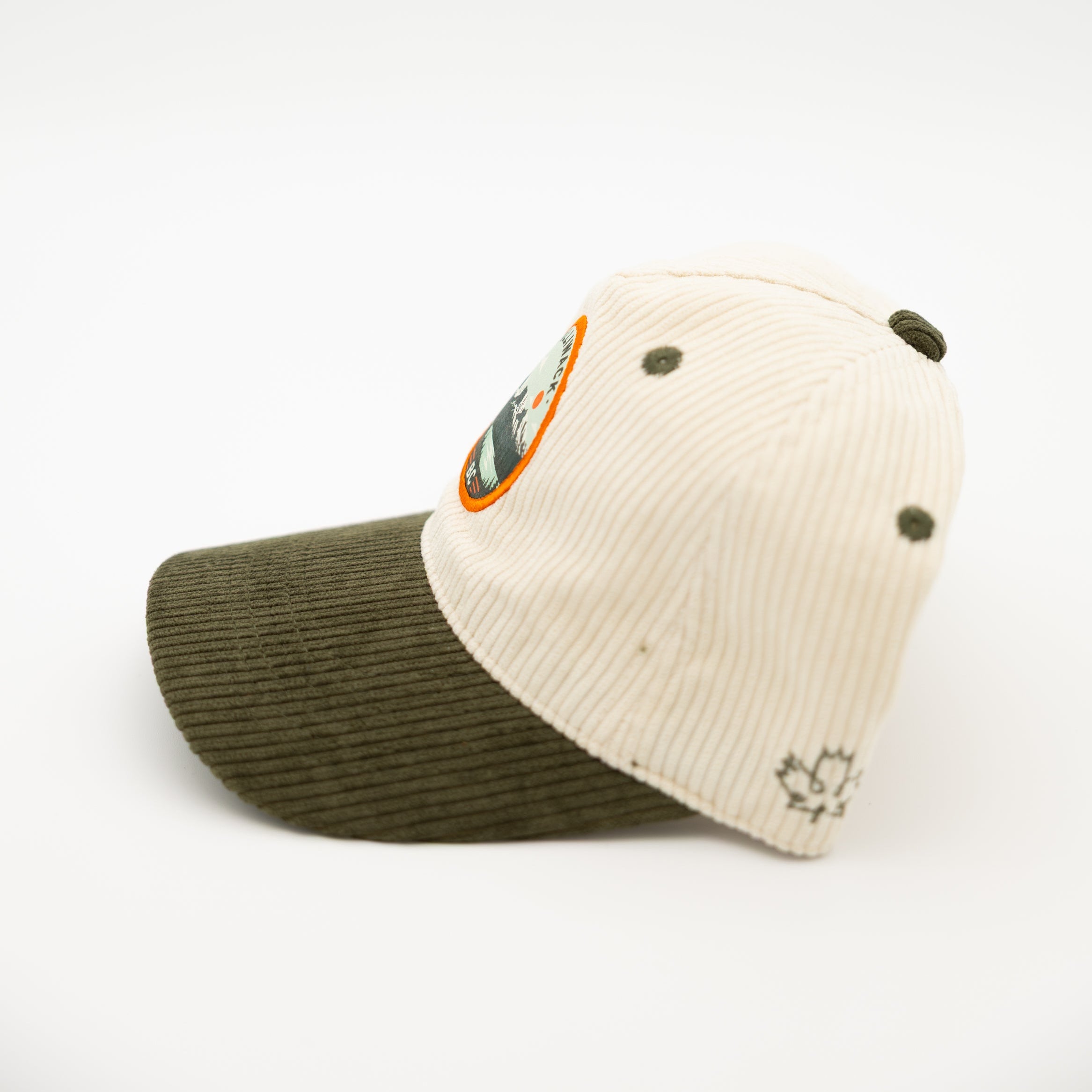 A two-tone corduroy baseball cap with an off-white crown and an olive green brim, featuring a circular 'chilliwack BC' logo patch on the front.