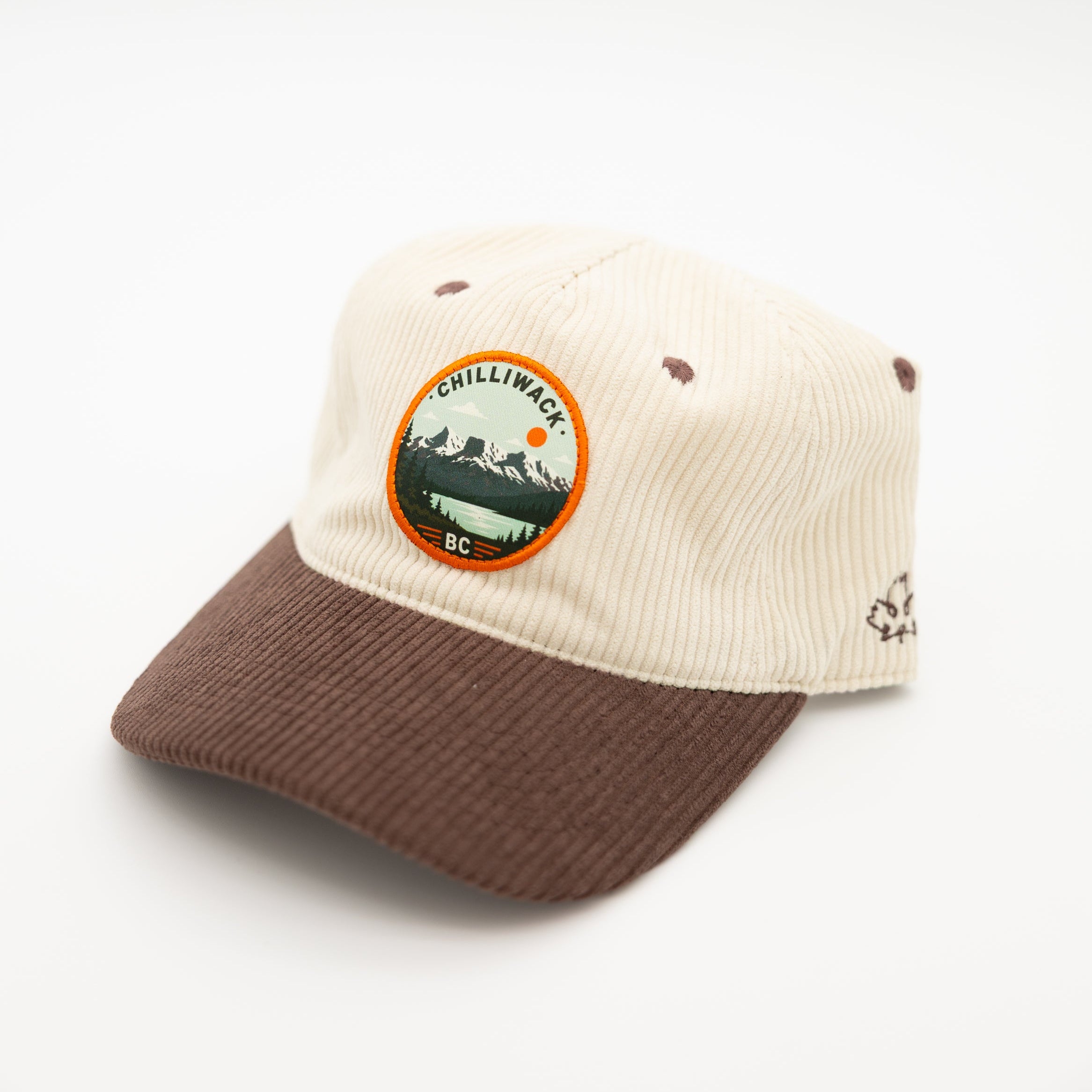 A two-tone corduroy baseball cap with an off-white crown and a brown visor, featuring a circular 'Chilliwack BC' patch on the front and a small embroidered logo on the side.