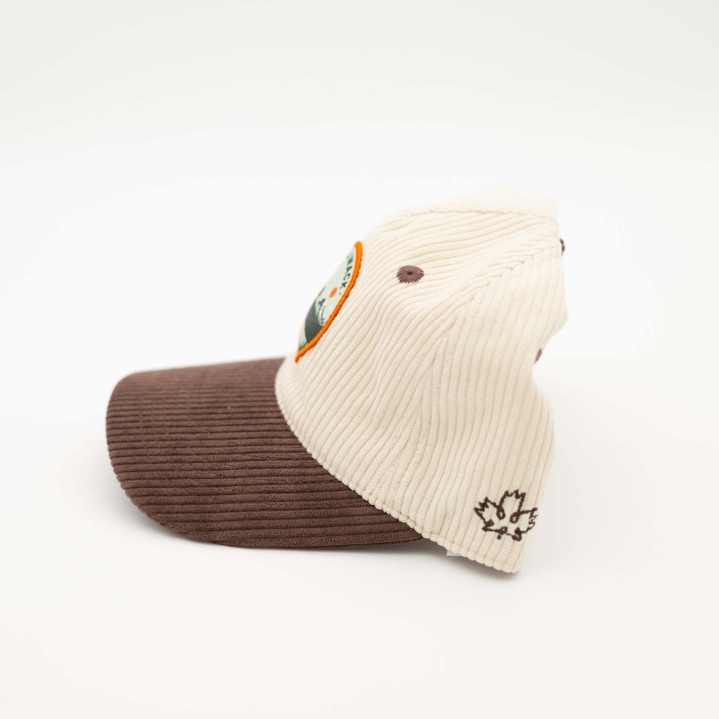 A two-tone corduroy baseball cap with an off-white crown and a brown visor, featuring a circular 'Chilliwack BC' patch on the front and a small embroidered logo on the side.