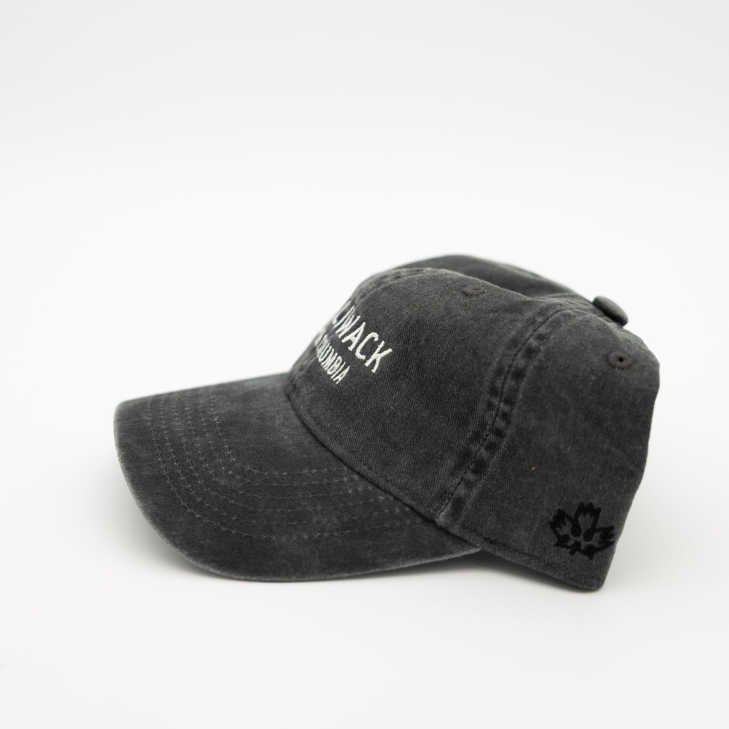 A washed black baseball cap with white embroidered text on the front and a small black maple leaf logo on the side, photographed on a seamless white background.